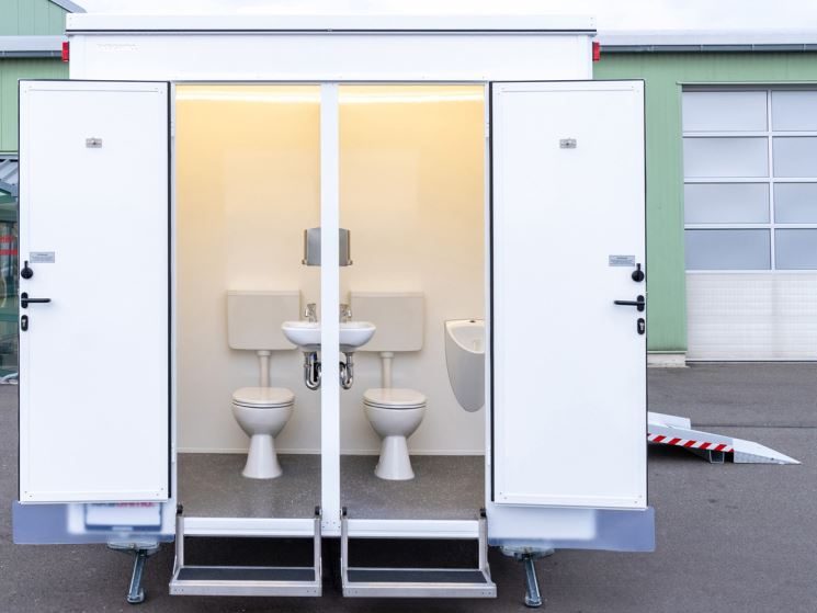 Außenansicht eines kleinen Toilettenwagens mit zwei Kabinen auf einem Hof